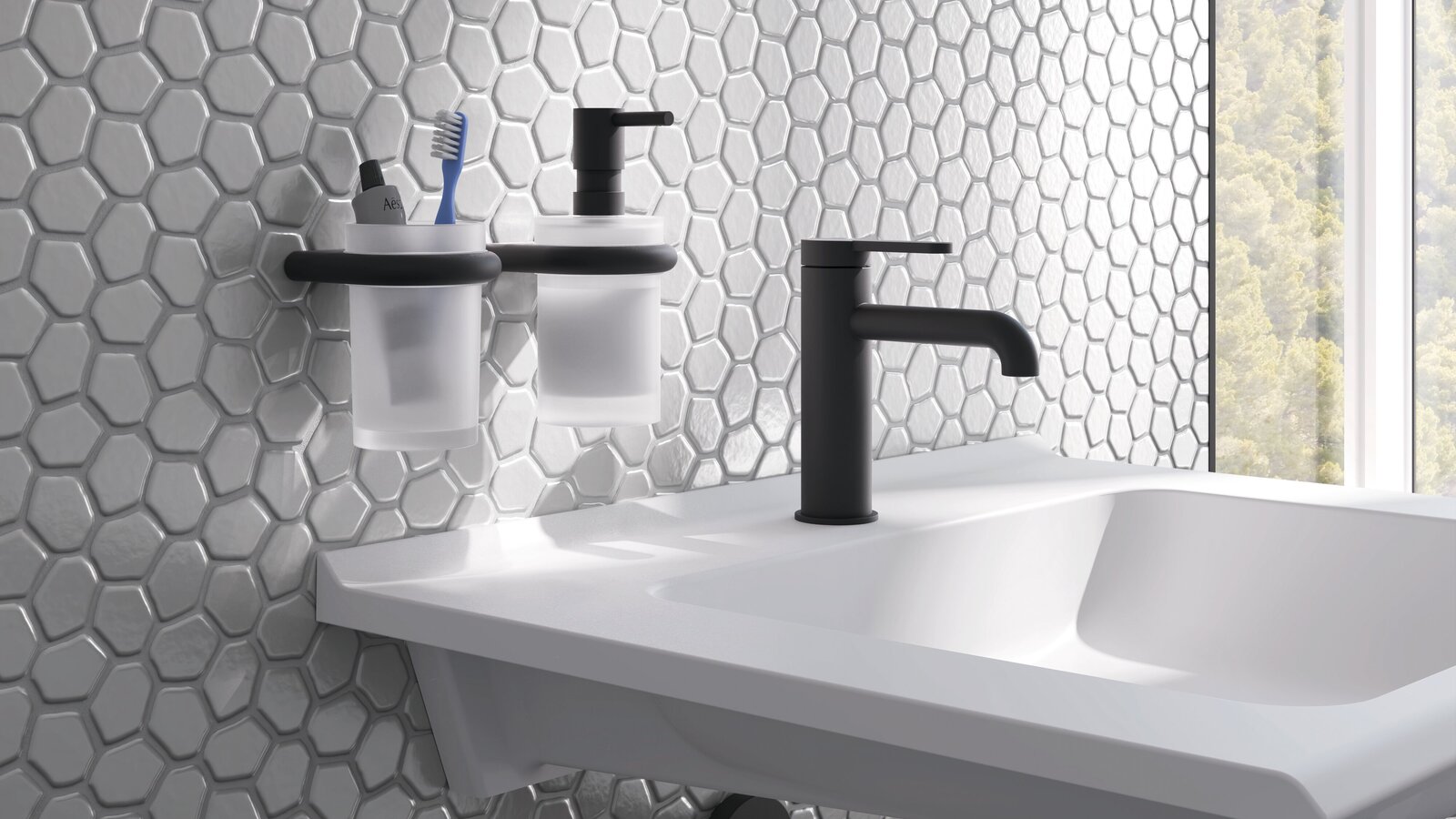 HEWI Fittings AQ477 A white washbasin with a black tap and two wall-mounted cups in black holders against a backdrop of grey tiles