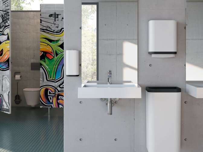 A white washbasin with a chrome-plated tap and a large mirrored wall, mounted on a grey concrete wall in the public WC