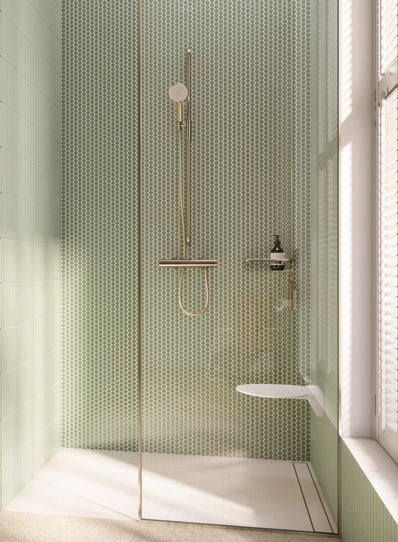 Wall-hung WC with flush handle and toilet roll holder, alongside a floor-level shower with a hinged seat and rail with shower head holder