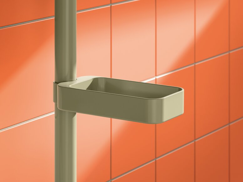 HEWI System 700 shower basket Green rectangular plastic shower basket with rounded corners attached to a vertical rail against an orange tiled wall