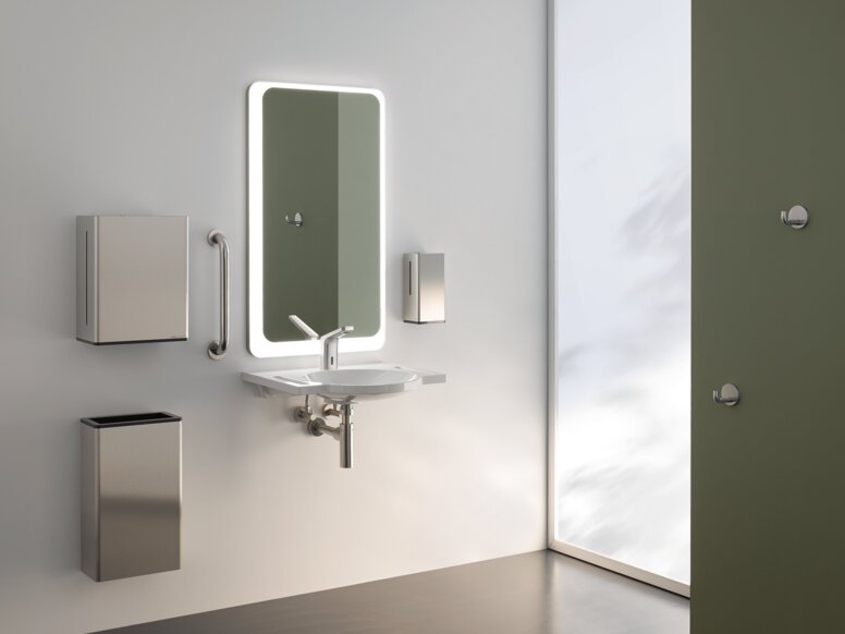 A lighted mirror, with a washbasin underneath, complete with a paper towel dispenser and a waste bin, against a white wall
