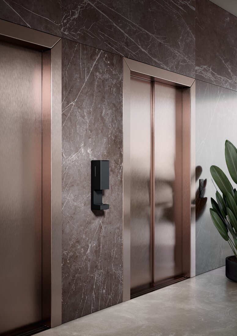HEWI System 900 SENSORIC Wall-mounted Disinfectant Dispenser Black powder-coated disinfectant dispenser installed next to two lift doors