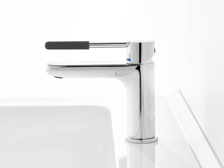 HEWI AQ single-lever washbasin mixer tap Chrome-plated tap with a long lever handle and dark grey grip sleeve on a white washbasin against a white background