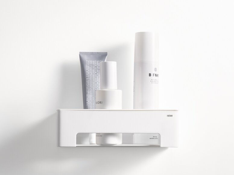 HEWI System 900 shower basket White wall-mounted shower basket with a shelf and an open compartment containing toiletries on a white wall