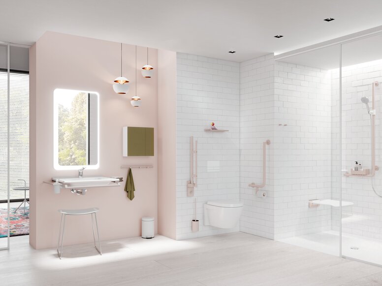 HEWI System 900 Bathroom Interior Bright bathroom with a pale pink feature wall, illuminated mirror above a white washbasin, wall-hung toilet and level-access shower with white wall tiles and light-coloured grab rails